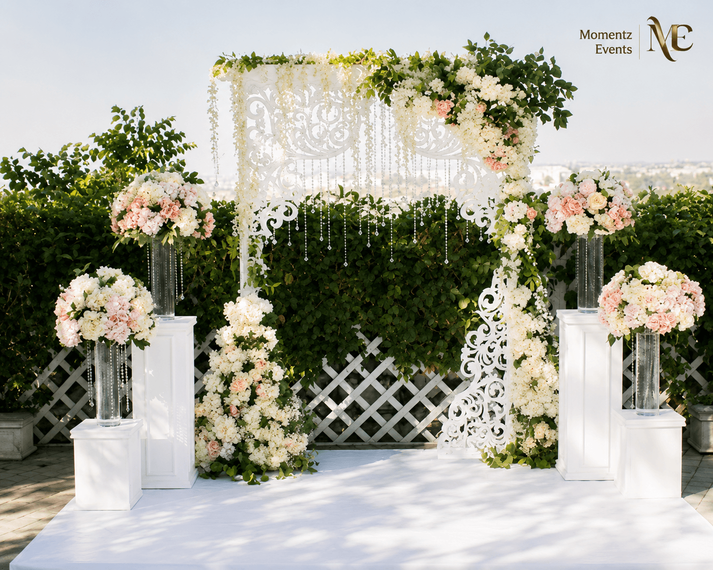 Outdoor wedding ceremony arch with white lattice panel and blush floral styling by Momentz Events