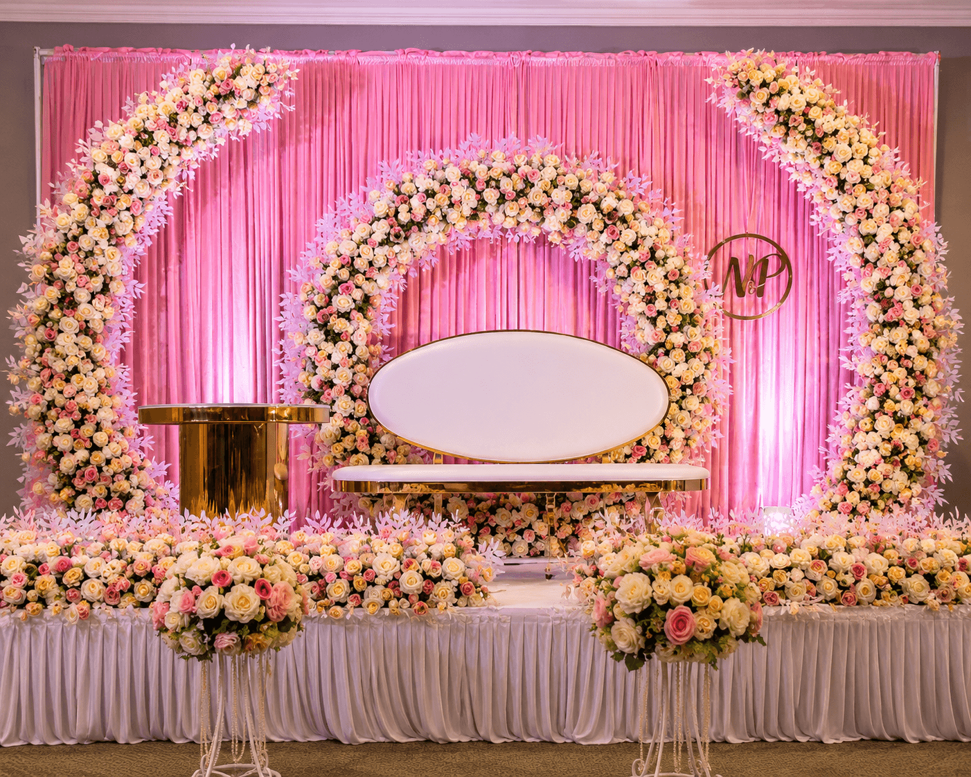 Pink floral wedding reception stage with a monogrammed backdrop, styled by Momentz Events